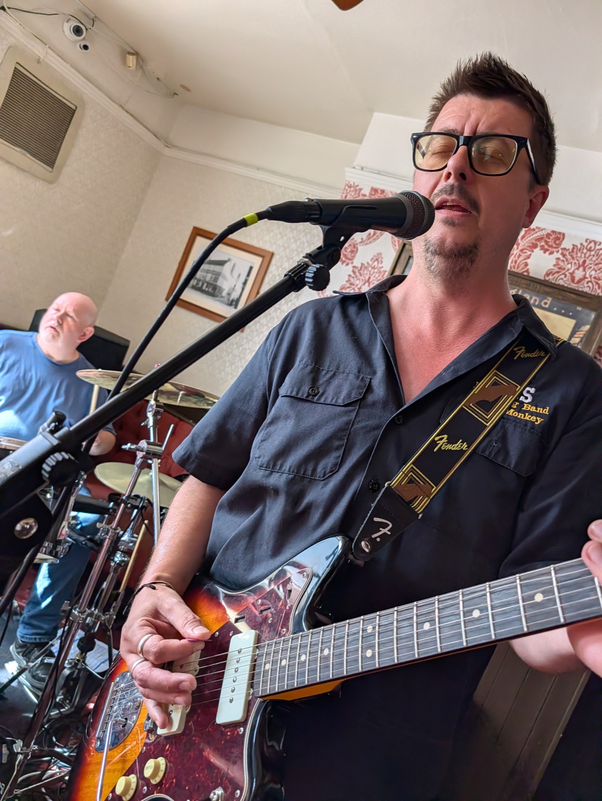 Rob Sherwood singing into the microphone while playing guitar